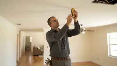 Fort Lauderdale electrician uses a stud finder to mark recessed lighting positions along ceiling joists