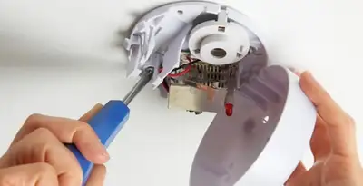Certified technician wiring smoke detector during installation in Fort Lauderdale, FL